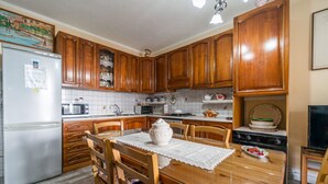 A kitchen with wooden cabinets, a refrigerator, a microwave, a stove, and a dining table with chairs.