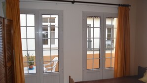 Een kamer met een bed, een raam met gordijnen en uitzicht op het balkon.