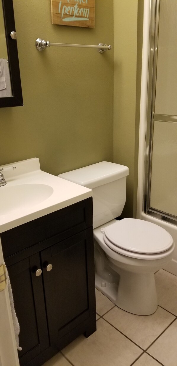 A bathroom with a white sink, black cabinet, white toilet, and a towel rack.