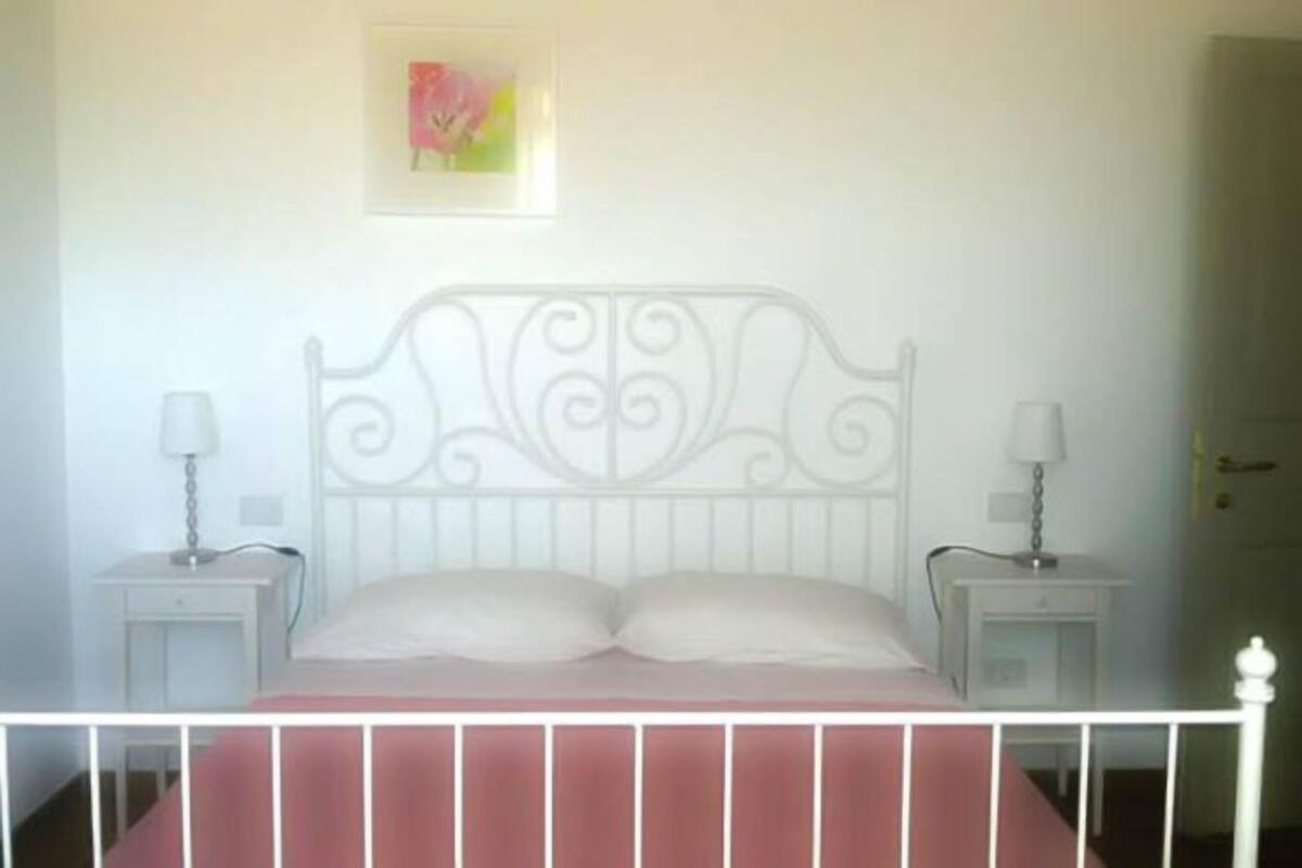A bed with a white metal headboard, two bedside tables with lamps, and a framed picture on the wall.