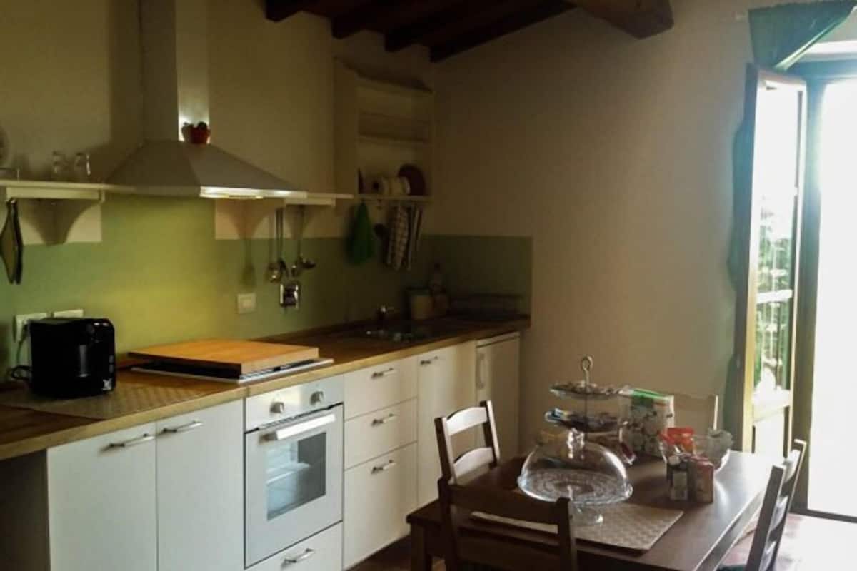 A kitchen with white cabinets, a wooden countertop, a coffee maker, and a dining table with chairs.