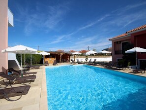 Una piscina al aire libre de temporada, sombrillas