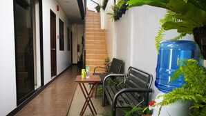 A corridor with a staircase, a table with a chair, and potted plants. - Lighthouse Apartment and Guest Inn (Puerto Princesa)