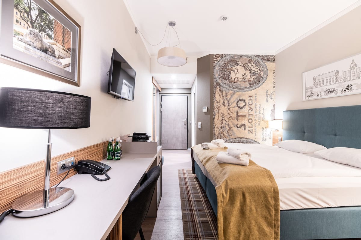 A hotel room with a bed, desk, chair, and a telephone.