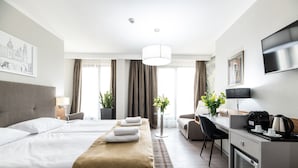 Ein Hotelzimmer mit Bett, Schreibtisch, einer Kaffeemaschine und einem Fernseher.