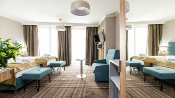 Une chambre d’hôtel avec deux lits, un canapé, une télévision et un coin repas.