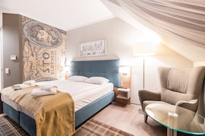 A hotel room with a bed, a chair, a glass table, a lamp, and a wall with a tapestry. - Perfect Hotel (Kraków)