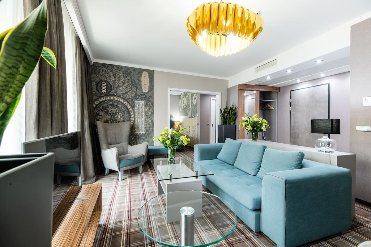 A modern living room with a sofa, a glass coffee table, and a decorative chandelier.