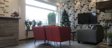 A modern living room with a fireplace, a television mounted on the wall, and a red sofa.