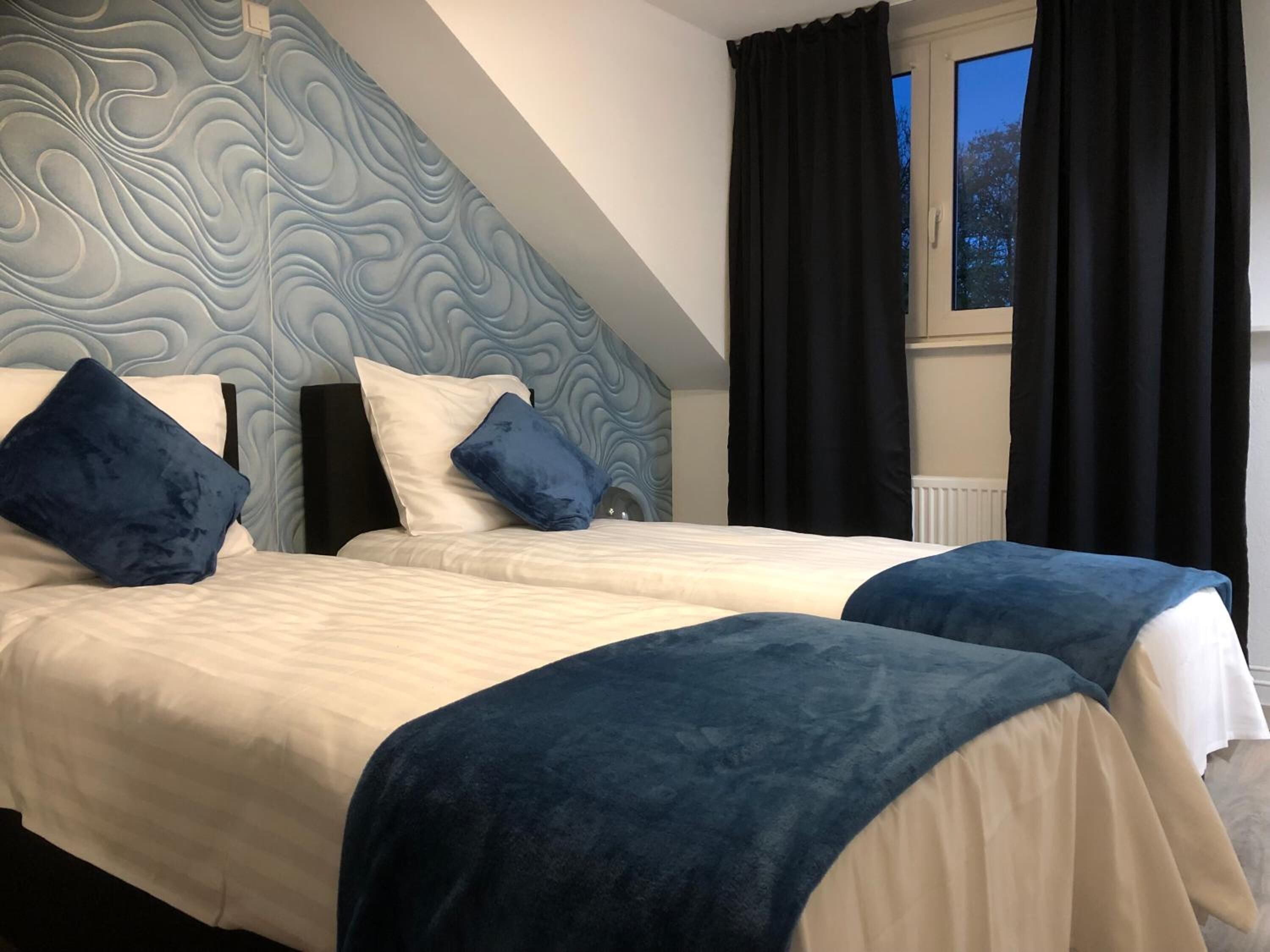 Een slaapkamer met twee bedden, een versierd plafond en een raam met gordijnen.