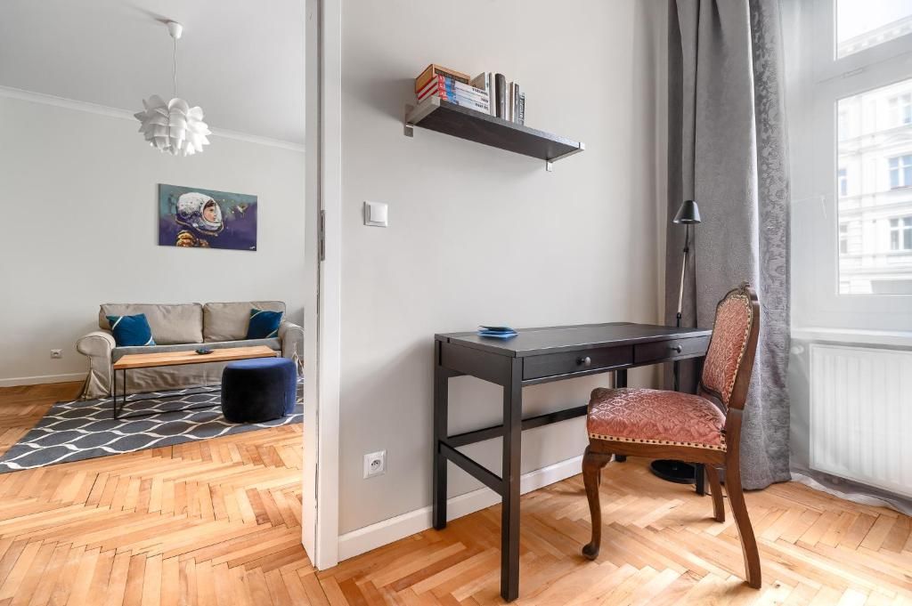 A room with a desk, a chair, a sofa, a bookshelf, and a painting.