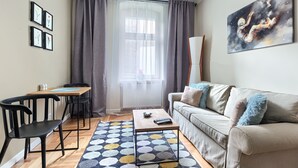 A living room with a sofa, chairs, a coffee table, and a painting on the wall. - MARGI Nell Apartament (Szczecin)