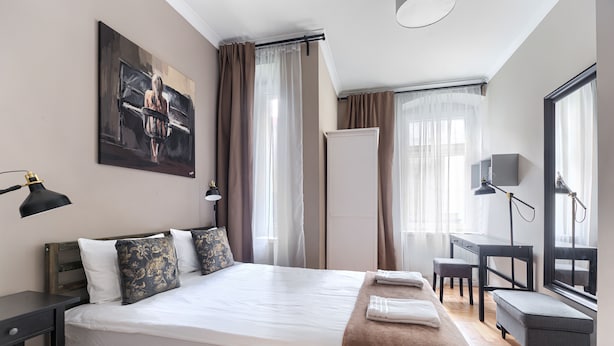 A modern hotel room with a large bed, a desk, and a chair. - MARGI Nell Apartament (Szczecin)