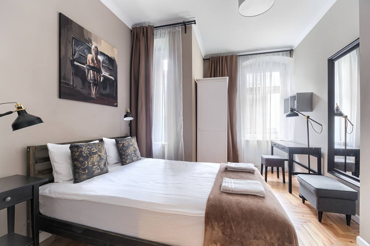 Habitación de hotel con una cama grande, un escritorio, una silla, un espejo y un cuadro en la pared.