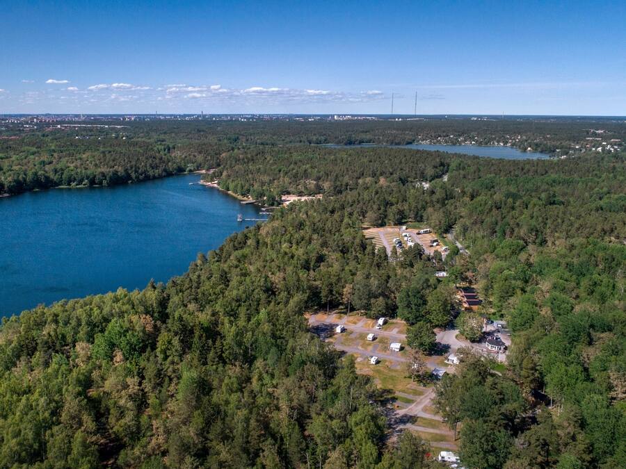 Vista aérea de una zona boscosa con un lago, un pequeño asentamiento y algunos edificios.