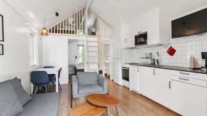 Una cocina moderna con armarios blancos, una mesa de comedor de madera y un sofá gris.