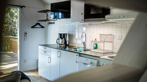 Una cocina compacta con armarios blancos, un lavavajillas Bosch, una cafetera y un hervidor.
