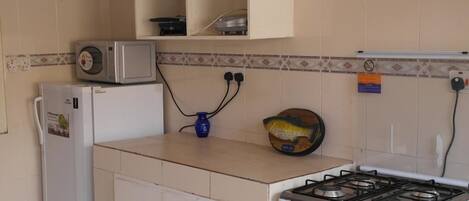 Una cocina con estufa, microondas y refrigerador.