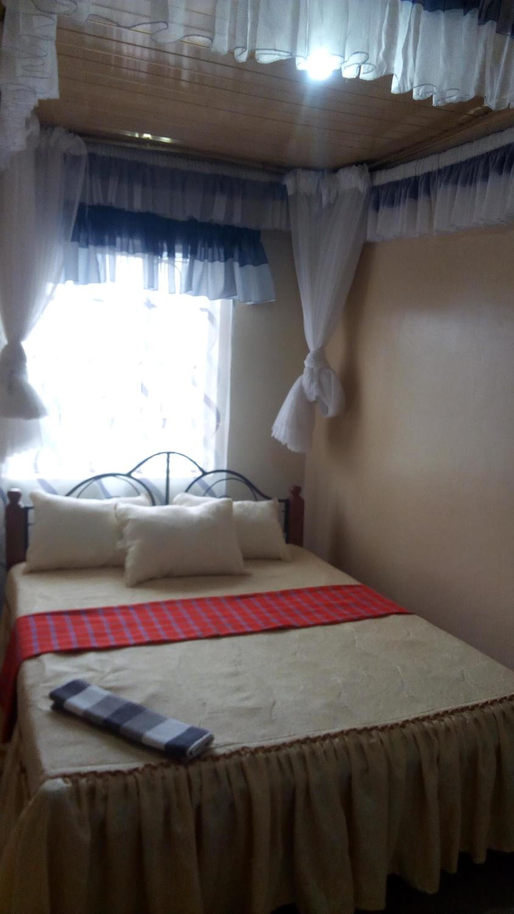A single bed with a red and blue checkered bedspread, white pillows, and a white canopy.