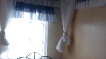 A single bed with a red and blue checkered bedspread, white pillows, and a white canopy.