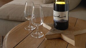 Una sala de estar acogedora con una mesa de madera, una botella de vino y dos copas.