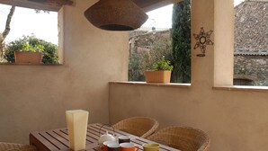 Una mesa de madera con una vela, juego de té y plantas en macetas.