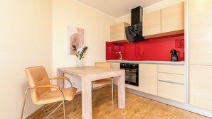 Uma cozinha moderna com mesa de madeira, duas cadeiras, painel de fundo vermelho e exaustor preto.