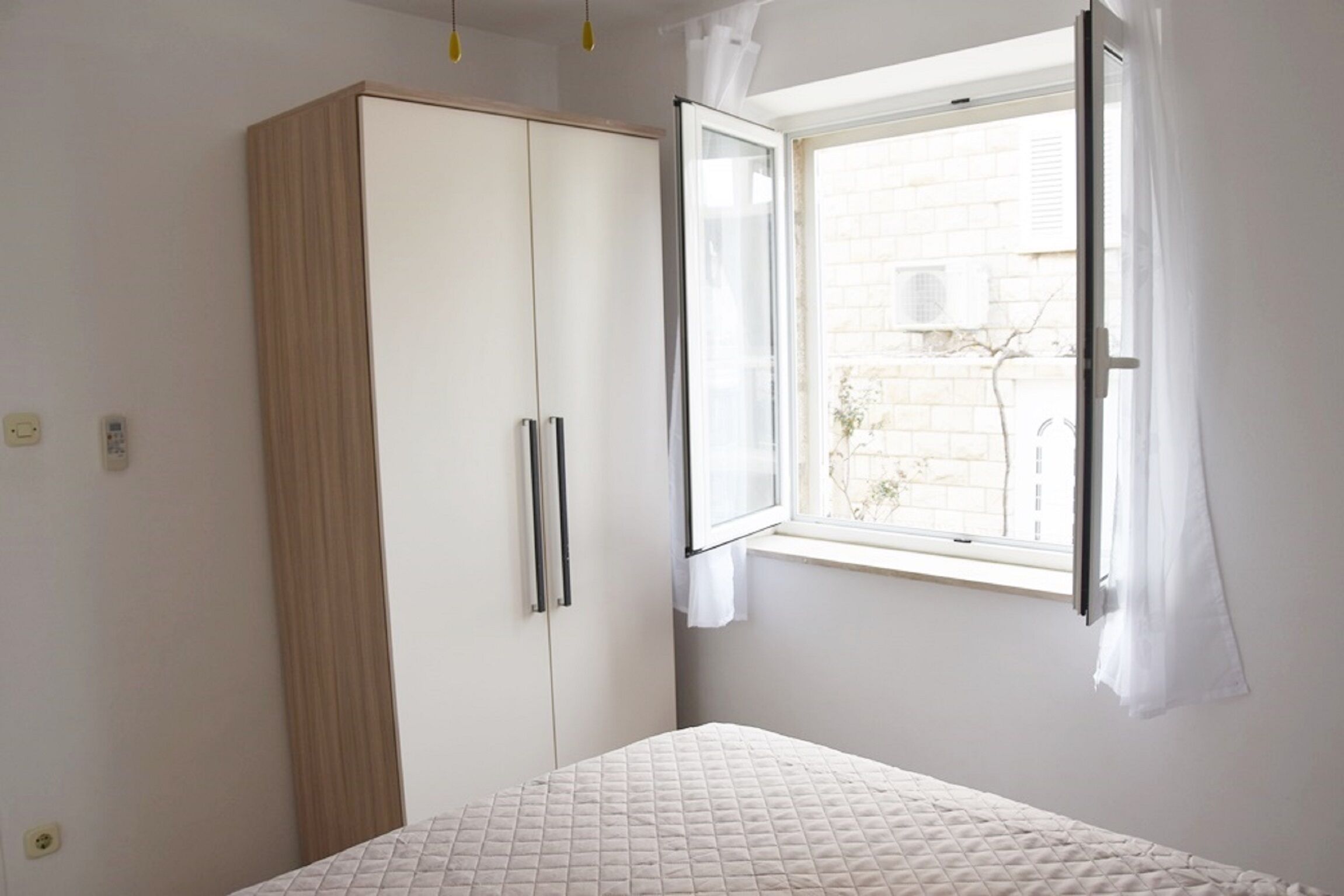 A bedroom with a bed, a wardrobe, and a window with curtains.