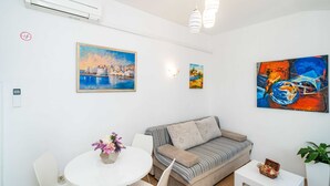 Una sala de estar moderna con un sofá, una mesa de comedor con sillas y obras de arte en las paredes.