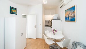 Una cocina moderna con armarios blancos, microondas y comedor con mesa y sillas blancas.