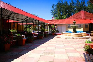 Un patio con suelo de baldosas, edificios de techo rojo y plantas en macetas.