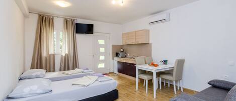 Une pièce de taille modeste comprenant un lit, une petite kitchenette, une table à manger avec des chaises et un canapé.