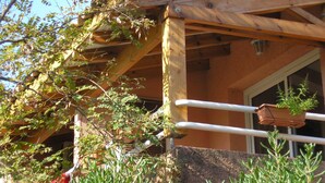 A wooden pergola structure with a window and a door, surrounded by greenery and a red cloth hanging. - HOLIDAY 'THE WATERFRONT' (Borgo)