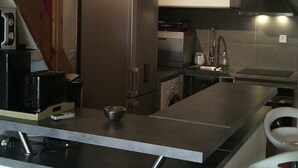 A kitchen with a central island, bar stools, a refrigerator, a microwave, and a clock on the wall. - HOLIDAY 'THE WATERFRONT' (Borgo)