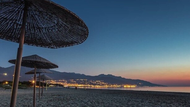 A beach with thatched umbrellas and a cityscape in the background. - HOLIDAY 'THE WATERFRONT' (Borgo)