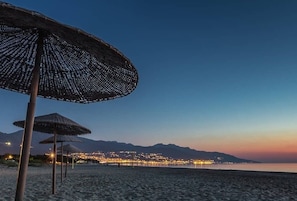 A beach with thatched umbrellas and a cityscape in the background. - HOLIDAY 'THE WATERFRONT' (Borgo)