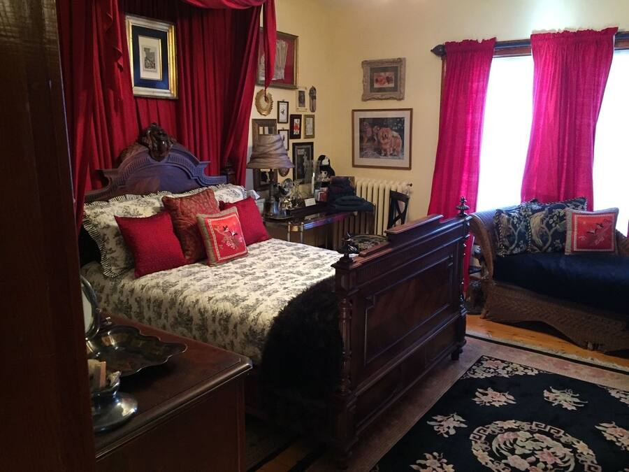 A traditional bedroom with a four-poster bed, a wooden dresser, and a sofa.