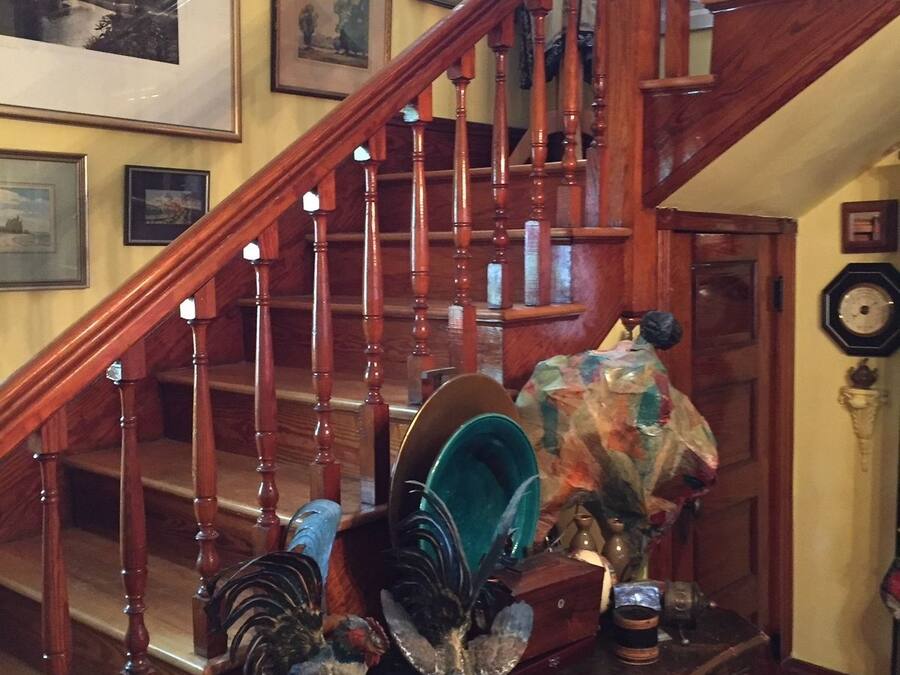 A wooden staircase with multiple steps and a handrail, leading to a landing area with a decorative chest and various items.