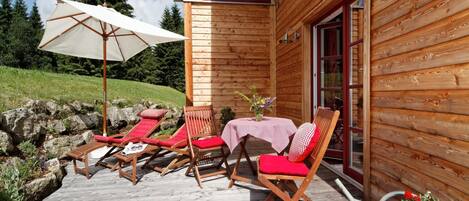 A wooden cabin with a deck, outdoor seating, and a table with a tablecloth.
