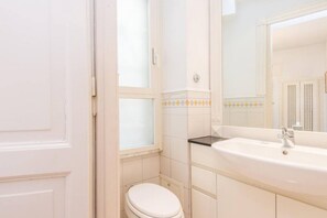 Een badkamer met toilet, wastafel en spiegel.