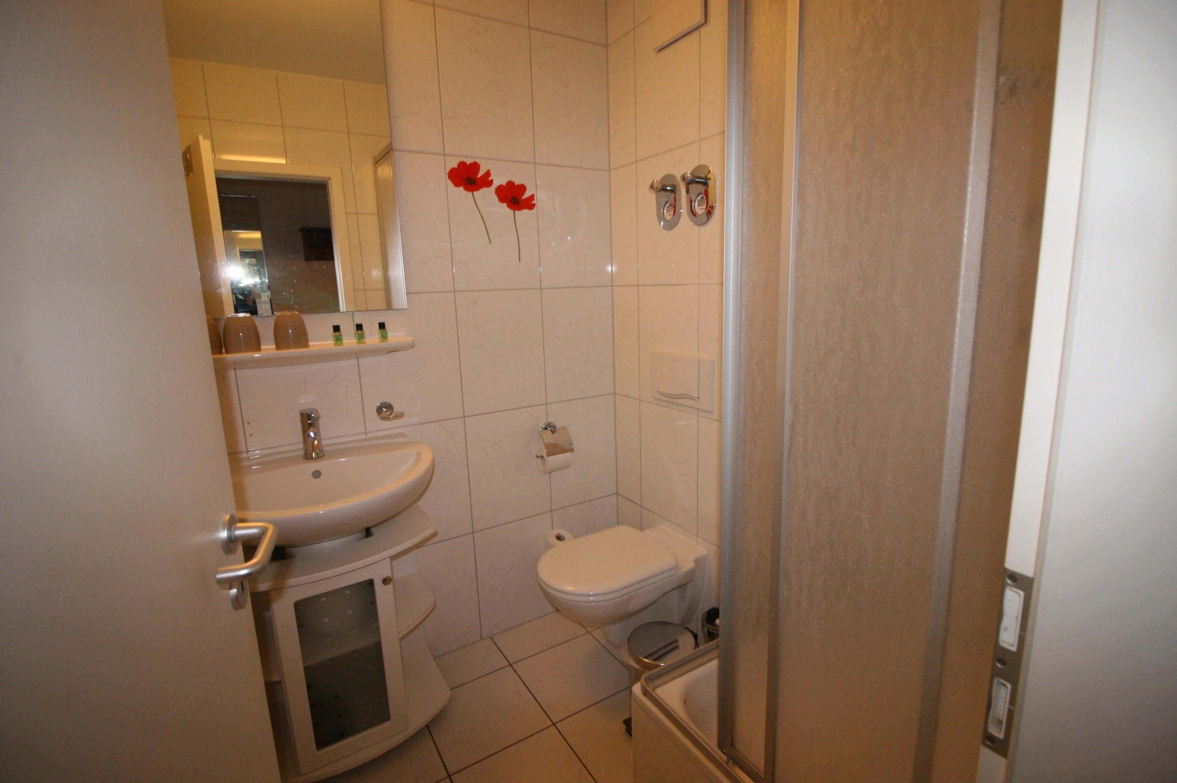 A small bathroom with a sink, toilet, and shower.