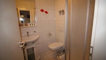Ein kleines Badezimmer mit Waschbecken, Toilette und Dusche.