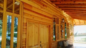 A wooden cabin with large windows, a porch, and a dining area. - Green Resort (San Martín Jilotepeque)