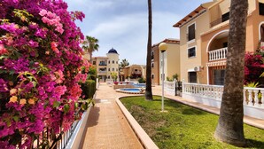 A hotel courtyard with a fountain, palm trees, and bougainvillea flowers.