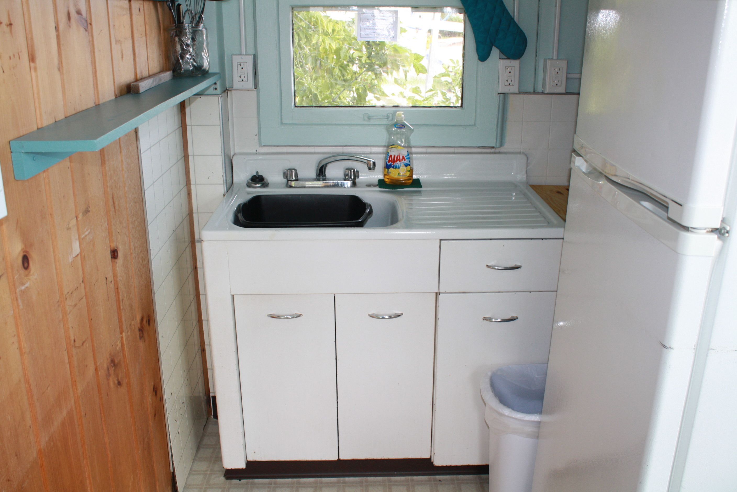 A compact kitchen with a sink, a window, and a refrigerator.