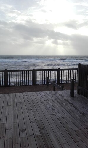 A wooden deck with a railing overlooking a stormy sea.