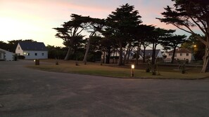 A residential area with houses, a paved driveway, and a grassy area with trees.