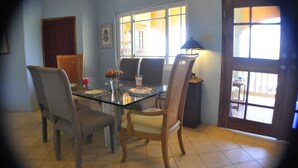 A dining area with a glass table, wicker chairs, and a view through a window. - Jah Freedom Inn Negril (Negril)