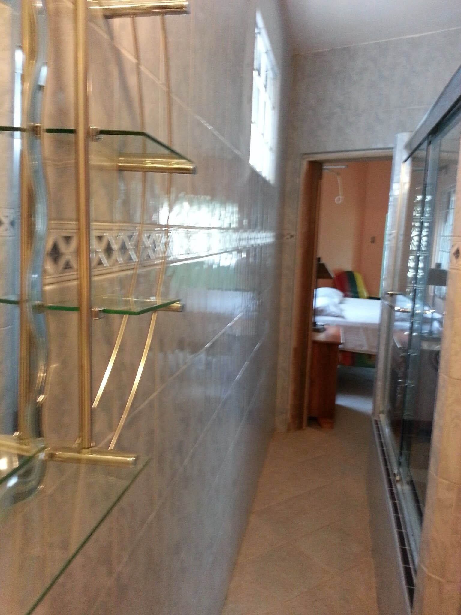 Un pasillo estrecho con un separador de vidrio en un lado, y una cama visible al otro lado.
