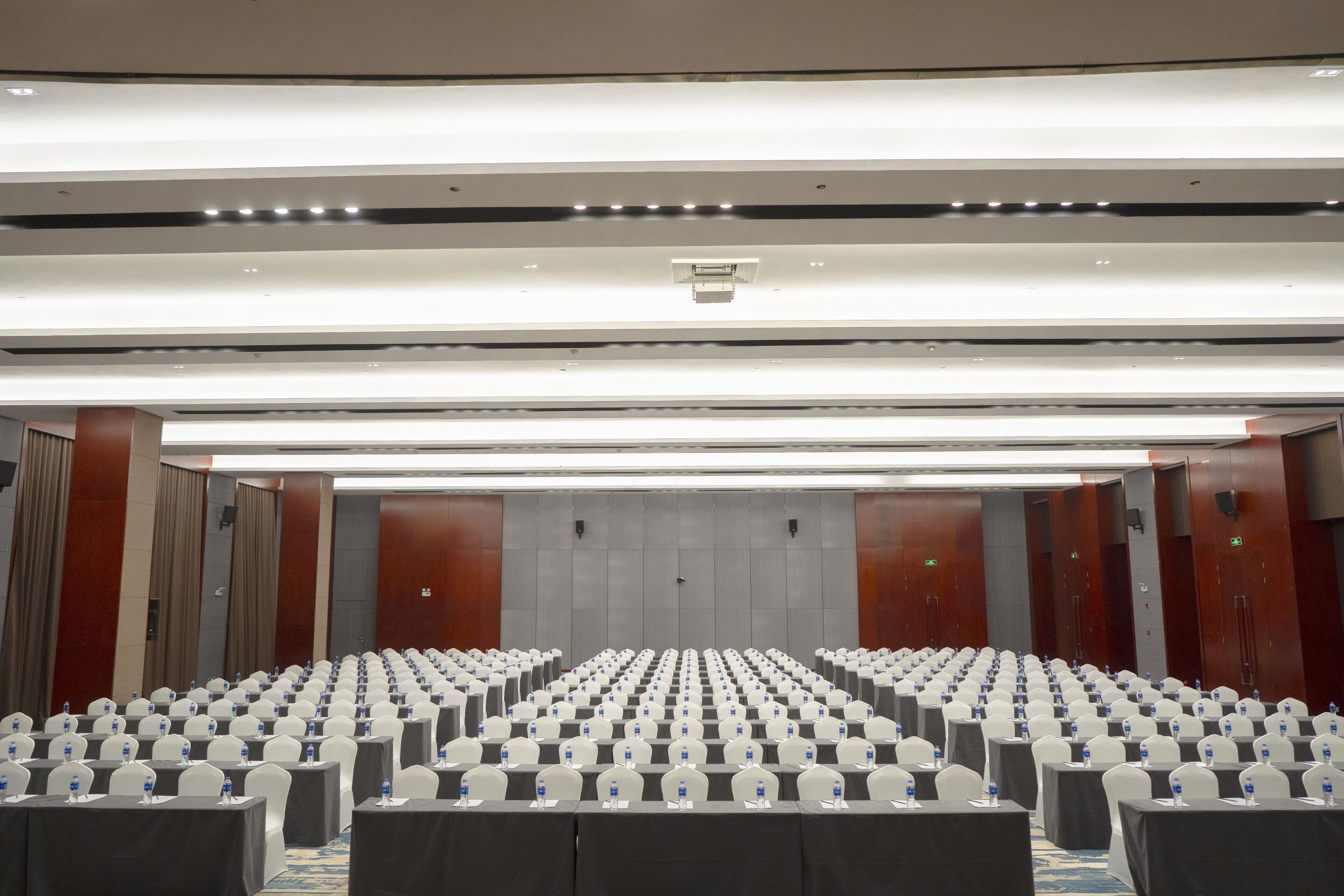 Une salle de conférence avec des rangées de tables et de chaises, équipée de bouteilles d’eau et de plaques nominatives.